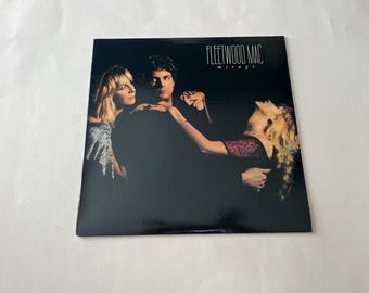 May include: A black vinyl record album cover with a photo of three people. The album is titled "Fleetwood Mac Mirage".