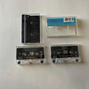 May include: Four cassette tapes, two are clear and two are black. The clear tapes have the text "MCA" and "MCA MUSIC" on them. The black tapes have the text "MCA" and "MCA MUSIC" on them. The clear tapes have the text "B" and "2" on them. The black tapes have the text "B" and "2" on them.