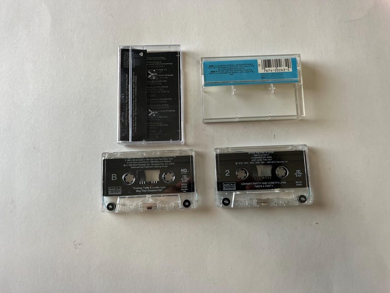 May include: Four cassette tapes, two are clear and two are black. The clear tapes have the text "MCA" and "MCA MUSIC" on them. The black tapes have the text "MCA" and "MCA MUSIC" on them. The clear tapes have the text "B" and "2" on them. The black tapes have the text "B" and "2" on them.