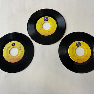 May include: Three black vinyl records with yellow labels. The labels feature the text "Madonna" and the song titles "Take a Bow", "Holiday", and "Like a Prayer".