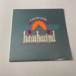 May include: A vintage vinyl record album cover with a blue background and the text "Church of Hawkwind" in white and red lettering. A stylized orange sun with wings is behind the text.