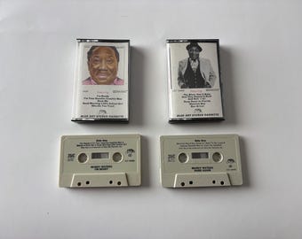 May include: Two vintage cassette tapes featuring Muddy Waters. One tape has a portrait of a man and the text "I'm Ready". The other tape has a black and white photo of a man and the text "The Blues Had a Baby". Both tapes are on a white background.