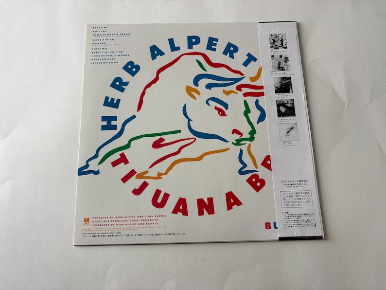 Puede incluir: Una portada del &aacute;lbum de Herb Alpert & The Tijuana Brass. La portada del &aacute;lbum es blanca con las palabras "Herb Alpert Tijuana Brass" en azul y rojo. Un gr&aacute;fico de toro colorido est&aacute; en el centro. El t&iacute;tulo del &aacute;lbum es "Bu".
