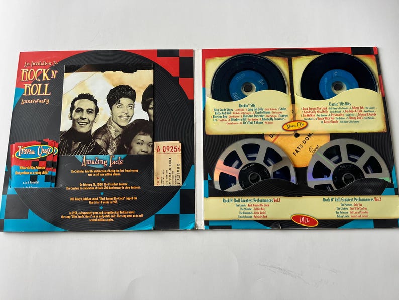 May include: A red, white, and blue themed Rock 'n' Roll Anniversary box set with a black and white checkered background. The box set includes a DVD, a trivia quiz, and a booklet with facts about Rock 'n' Roll. The front of the box features a photo of three musicians.