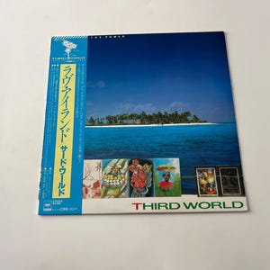 May include: A vinyl record album cover featuring a tropical island scene with a blue sky and ocean. The album is titled "The Power" by "Third World" and features the text "ブラック・アンド・グリーン・サード・ワールド" in Japanese.
