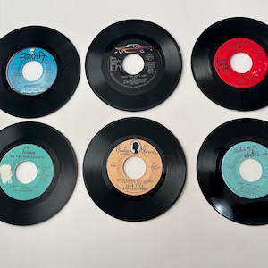 May include: Six black vinyl records with different labels and titles. The labels are in various colors, including red, blue, and white. The records are all 45 RPM.
