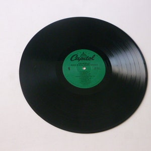 Op de afbeelding: Zwarte vinylplaat met een groen label waarop "Capitol" en "The Beatles" staat, met de albumtitel "A Hard Day's Night" in wit.