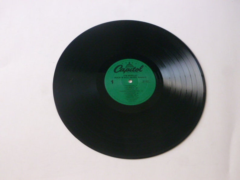 Op de afbeelding: Zwarte vinylplaat met een groen label waarop "Capitol" en "The Beatles" staat, met de albumtitel "A Hard Day's Night" in wit.