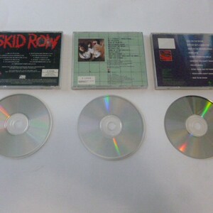 May include: Three compact discs with their original cases. The cases are all black with white text. The first case has the band name "SKID ROW" printed on the front. The second case has a band photo on the front. The third case has a band logo on the front.