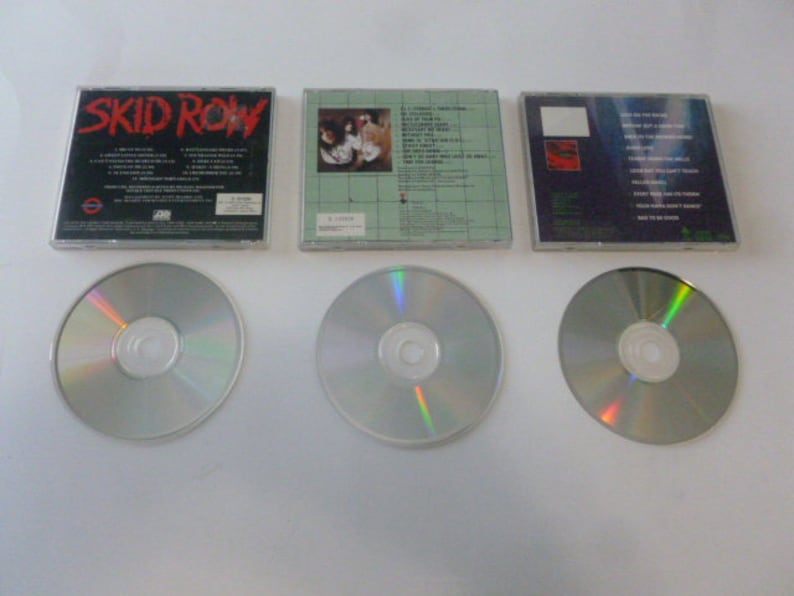 May include: Three compact discs with their original cases. The cases are all black with white text. The first case has the band name "SKID ROW" printed on the front. The second case has a band photo on the front. The third case has a band logo on the front.