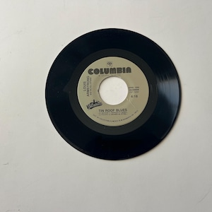 May include: A black vinyl record with a Columbia Records label. The label features a photo of Louis Armstrong and the song title "Tin Roof Blues".