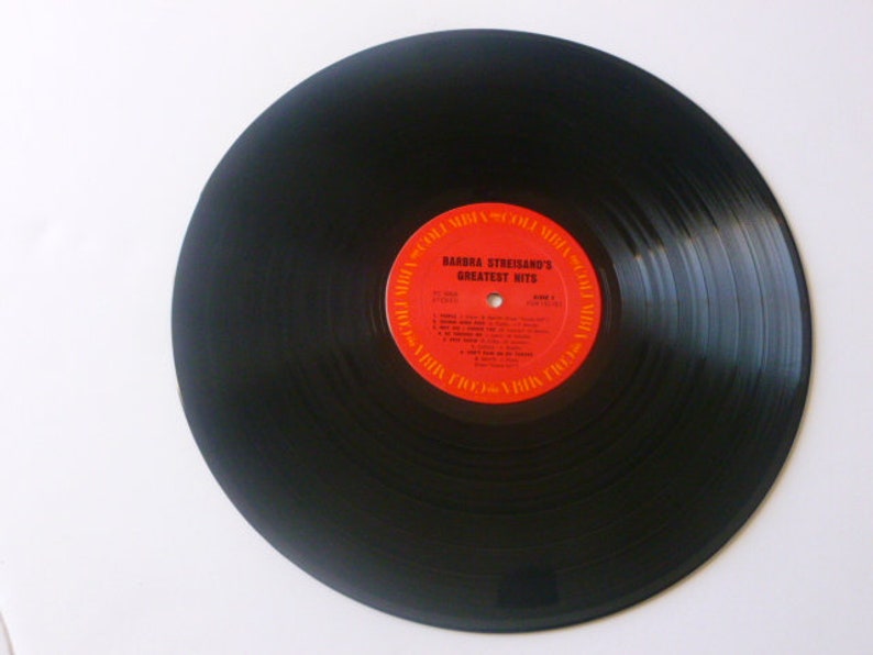 May include: Black vinyl record with a red and orange label that reads "Barbra Streisand's Greatest Hits".