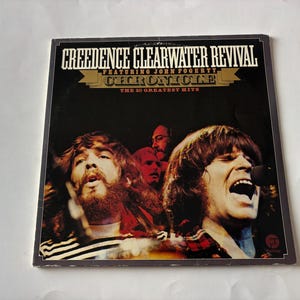 May include: A square vinyl record cover for Creedence Clearwater Revival featuring John Fogerty, titled Chronicle: The 20 Greatest Hits. The cover displays a dark, moody photograph of the band members performing, with white and gold text.