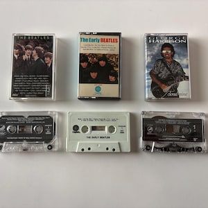 May include: Six vintage cassette tapes featuring The Beatles and George Harrison albums. The tapes include "The Beatles", "The Early Beatles", and "Cloud Nine". The cassette cases are clear plastic, with album art and text visible.