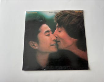 May include: Album cover for "Milk and Honey" by John Lennon and Yoko Ono. The cover features a close-up of the couple kissing, with a soft, blurred background. The album title and artist names are visible at the top.