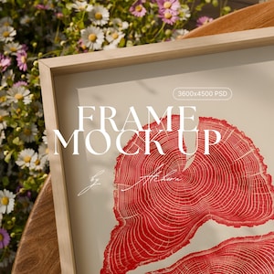 May include: A wooden framed print mockup featuring a red tree ring design. The words "FRAME MOCK UP" are displayed in large, bold letters. The image is set against a soft, neutral background.