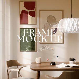 Puede incluir: Una escena de habitación con arte enmarcado, una mesa de madera y sillas. El arte incluye diseños abstractos en rojo, verde y beige. Una lámpara de papel blanca cuelga sobre la mesa, que tiene una taza, un libro y un móvil.