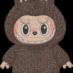Op de afbeelding: Geborduurd pluche speelgoed in de vorm van een wezen met een bruin, getextureerd lichaam en een lachend gezicht. Het wezen heeft grote, ovale ogen met stervormige highlights, een kleine neus en een brede grijns met zichtbare tanden. De oren zijn lichtbruin.