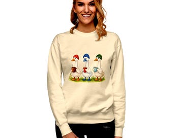 May include: A cream-coloured sweatshirt with a charming illustration of three geese, each wearing a hat and holding a mug. The geese are in red, blue, and green hats, each with a different coloured mug. The sweatshirt has a relaxed fit.