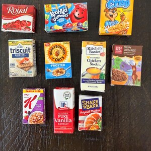 May include: A collection of miniature food product boxes, including Royal Strawberry gelatin, Kool-Aid Jammers, Post Golden Crisp cereal, Triscuit crackers, Honey Bunches of Oats, Kitchen Basics chicken stock, and Mom's Crispy Cocoa Rice cereal.