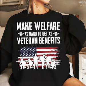 May include: Black sweatshirt featuring the text "MAKE WELFARE AS HARD TO GET AS VETERAN BENEFITS" in white. The design includes an American flag and soldier silhouettes. A patriotic themed garment.