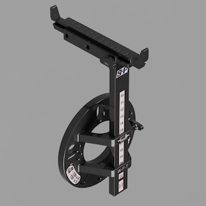 Könnte beinhalten: Ein schwarzes mechanisches Gerät mit einem kreisförmigen Bauteil und einem vertikalen Balken mit Messmarkierungen. Das Gerät hat einen rechteckigen oberen Abschnitt und ist vor einem grauen Hintergrund platziert. Das Gerät trägt den Text "SP".