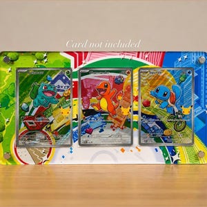 May include: A rectangular acrylic display frame featuring three slots for trading cards, decorated with colorful graphic illustrations of Bulbasaur, Charmander, and Squirtle. The frame has silver hardware at the corners and includes the text Card not included.