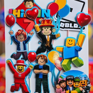以下が含まれることがあります： Robloxのキャラクターと風船が描かれた、カラフルなケーキトッパー。「Hi In 7」の文字と、様々な衣装を着たRobloxのキャラクターが描かれています。赤、黄、青の風船も含まれています。