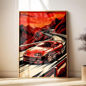 May include: A framed wall art print featuring a red sports car driving along a winding mountain road. The scene is rendered in a bold, graphic style with a vibrant red and orange sunset sky, dark mountain silhouettes, and motion blur lines.