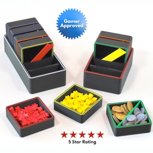 May include: Black and gray game organizers with red, yellow, and green accents. The organizers hold red, yellow, and gold game pieces. The image includes a "Gamer Approved" badge and a "5 Star Rating" graphic.