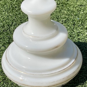 May include: A white ceramic mug with a black handle and the text "But First, Coffee" in a black, handwritten-style font. The mug is on a white surface.