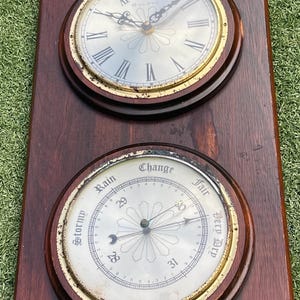 May include: A vintage Bulova weather station with a clock and barometer. The clock has Roman numerals and gold trim. The barometer indicates weather conditions. The wooden frame is dark brown.
