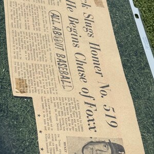 May include: Vintage newspaper clipping with the headline "Mick Slugs Homer No. 519." The article discusses a baseball game, featuring a photo of Mickey Mantle. The paper is aged with visible creases and text.