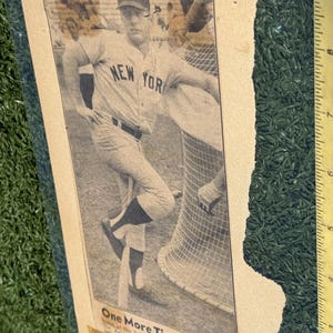 May include: Vintage black and white newspaper clipping featuring baseball player Mickey Mantle in a New York Yankees uniform. The headline reads "One More Time." The image is framed and set against a green background.