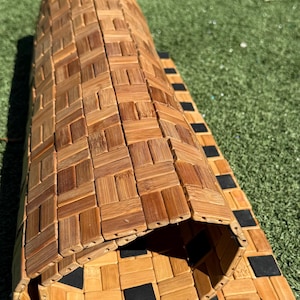 May include: Rolled-up bamboo mat with a woven, square pattern in shades of light and dark brown. The mat has a black border on one end and is partially unrolled, revealing the underside.