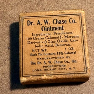May include: A vintage Dr. A. W. Chase Co. Ointment tin. The rectangular box is tan with black text, including the product name, ingredients, and manufacturer's information. The net weight is 1 oz.