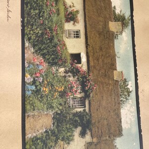 May include: A vintage postcard featuring a quaint cottage with a thatched roof, surrounded by lush greenery and vibrant flowers. The cottage has multiple windows and is partially covered in climbing plants. The text "A Newport Garden" is visible.