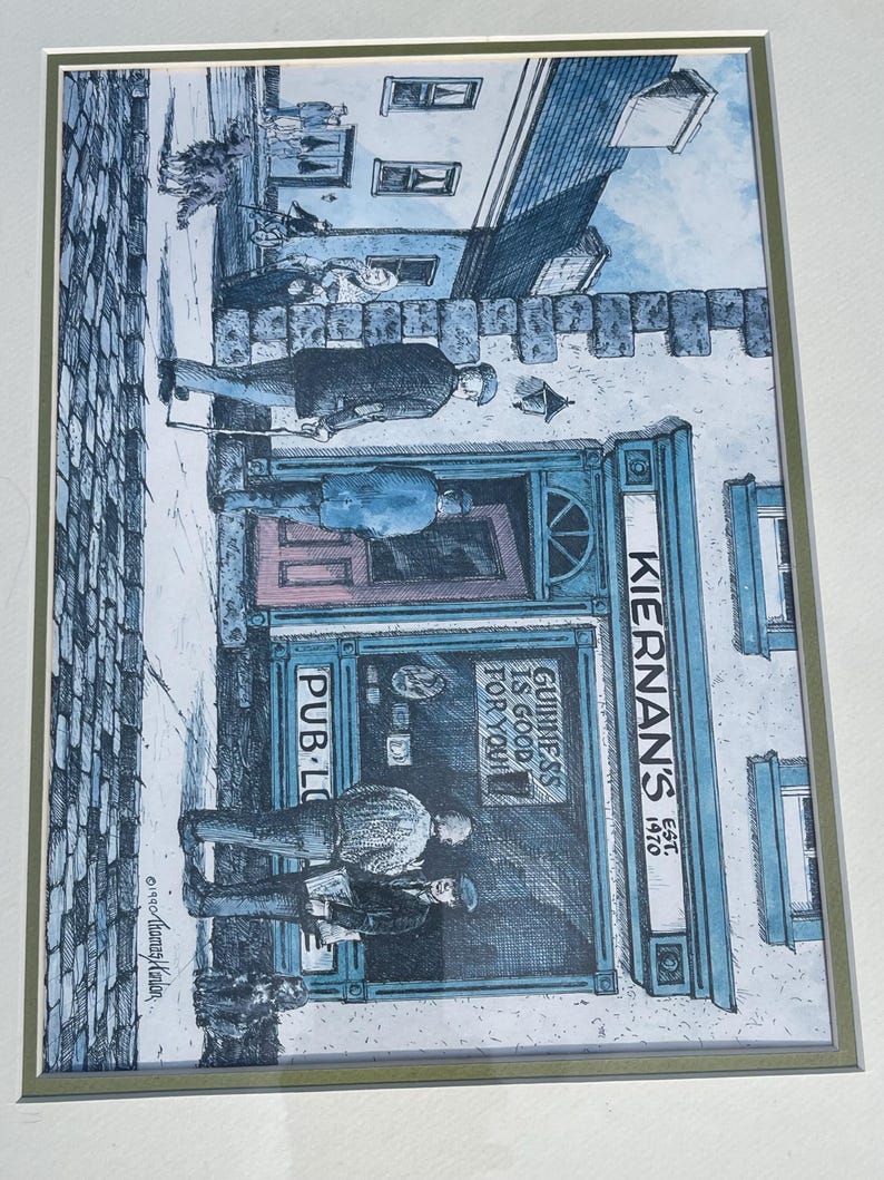 May include: An artistic print of Kiernan's Pub, with the text "Guinness is good for you!" and "Pub-Lo". The illustration depicts people outside the pub, with a blue and white color scheme. The pub's name and establishment year, 1970, are also visible.