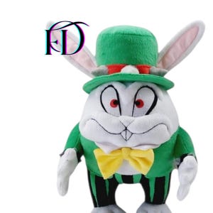 May include: A plush toy of a rabbit character wearing a green jacket, top hat, and a yellow bow tie. The rabbit has white fur, pink-lined ears, and red eyes. The jacket has black and green striped pants.