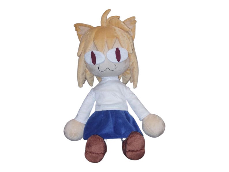 May include: A plush doll featuring a cat-like character with tan fur, large red eyes, and a white shirt and blue skirt. The doll has rounded limbs and brown shoes. The overall design is cartoonish and whimsical.