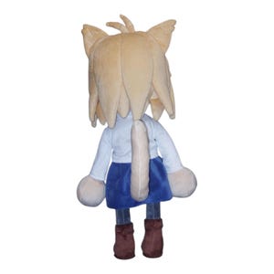 May include: A plush doll of a cat-like character, viewed from the back. It has tan fur, a white shirt, a blue skirt, and brown boots. The doll has large, round hands and a long tail.