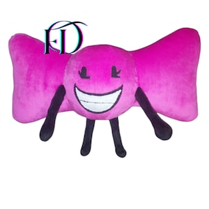May include: A plush toy in the shape of a pink bow with a smiling face. The face is a circle with black eyes and a white mouth. It has black arms and legs. The letters "FD" are in the upper left corner.