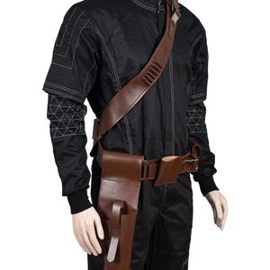 May include: A black jumpsuit with white stitching and a brown leather shoulder strap with bullet holders. A brown leather belt with pouches and a holster is also included. The outfit is displayed on a mannequin.