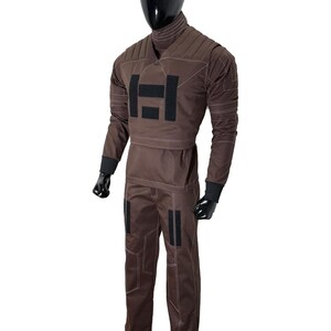 May include: Brown jumpsuit with a high collar and long sleeves. The suit features a padded chest and upper arm design, with black accents and white stitching. The pants have black patches on the knees. The mannequin is wearing black gloves.