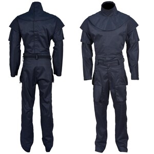 May include: Navy blue jumpsuit with a high collar and shoulder detailing. The one-piece garment features long sleeves, a belt at the waist, and multiple pockets on the legs. The jumpsuit is displayed from the front and back.