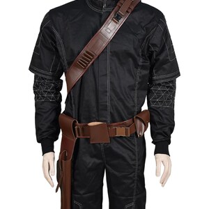 May include: Black jumpsuit with white stitching and a brown leather belt and shoulder strap. The costume includes a holster and a shoulder strap with multiple compartments. The sleeves have a geometric design.