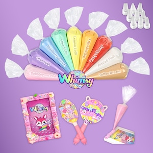 Puede incluir: Una colección de mangas pasteleras coloridas con varios sabores, incluyendo "Bubblegum Pink" y "Berry Cherry", dispuestas en forma de abanico. La imagen también presenta artículos de artesanía decorativos, incluyendo un marco de fotos y dos paletas decorativas, todos con el logo "Whimsy".