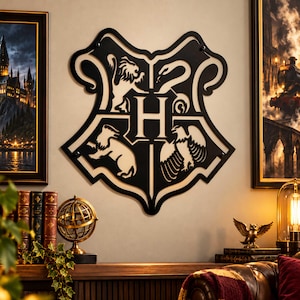 May include: A black, laser-cut wall decoration shaped like a shield, featuring a central letter H surrounded by four distinct animal silhouettes representing a lion, a snake, a badger, and an eagle, mounted on a light-colored wall surface.