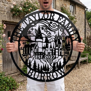 May include: A circular black metal wall sign featuring a laser-cut design of a castle silhouette, pine trees, and stars. The text "THE TAYLOR FAMILY" is arched at the top, "EST. 2027" is in the center, and "BURROW" is at the bottom of the frame.