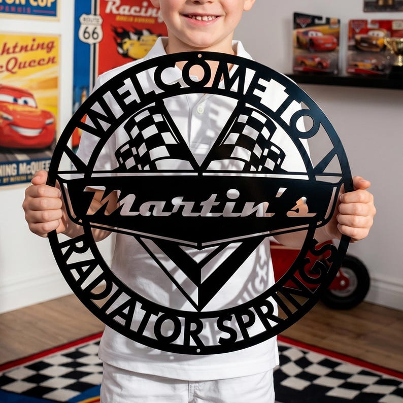 May include: A black metal sign with the words "WELCOME TO RADIATOR SPRINGS" in a circular design. The sign features two checkered flags and the name "Martin's" in the center. The sign is held by a person.